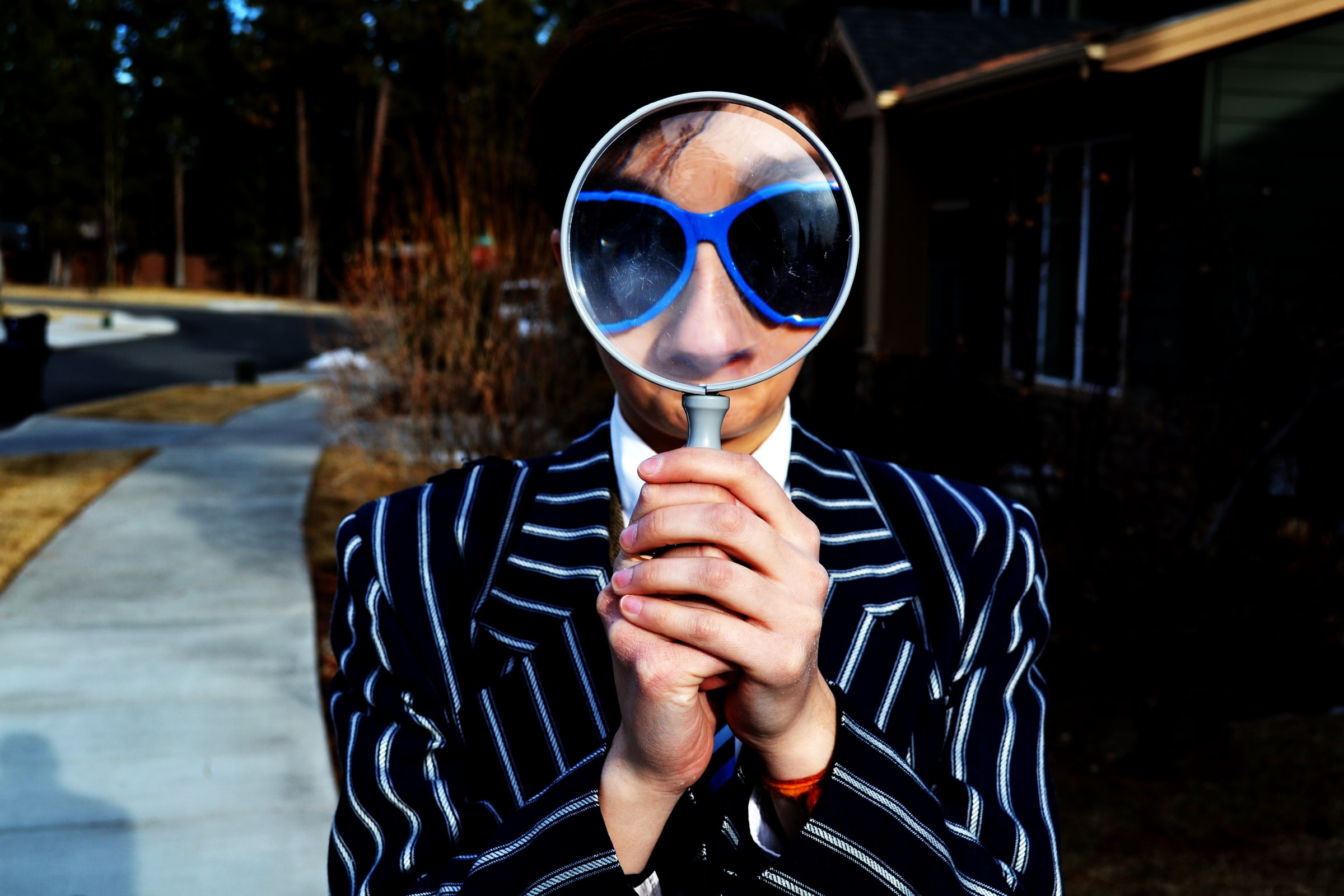 A person holds up a magnifying glass in front of their face.