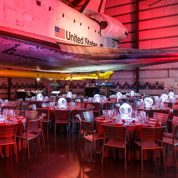 Seated Dinner under the Samuel Oschin Pavilion lit deep red with glowing globe centerpieces