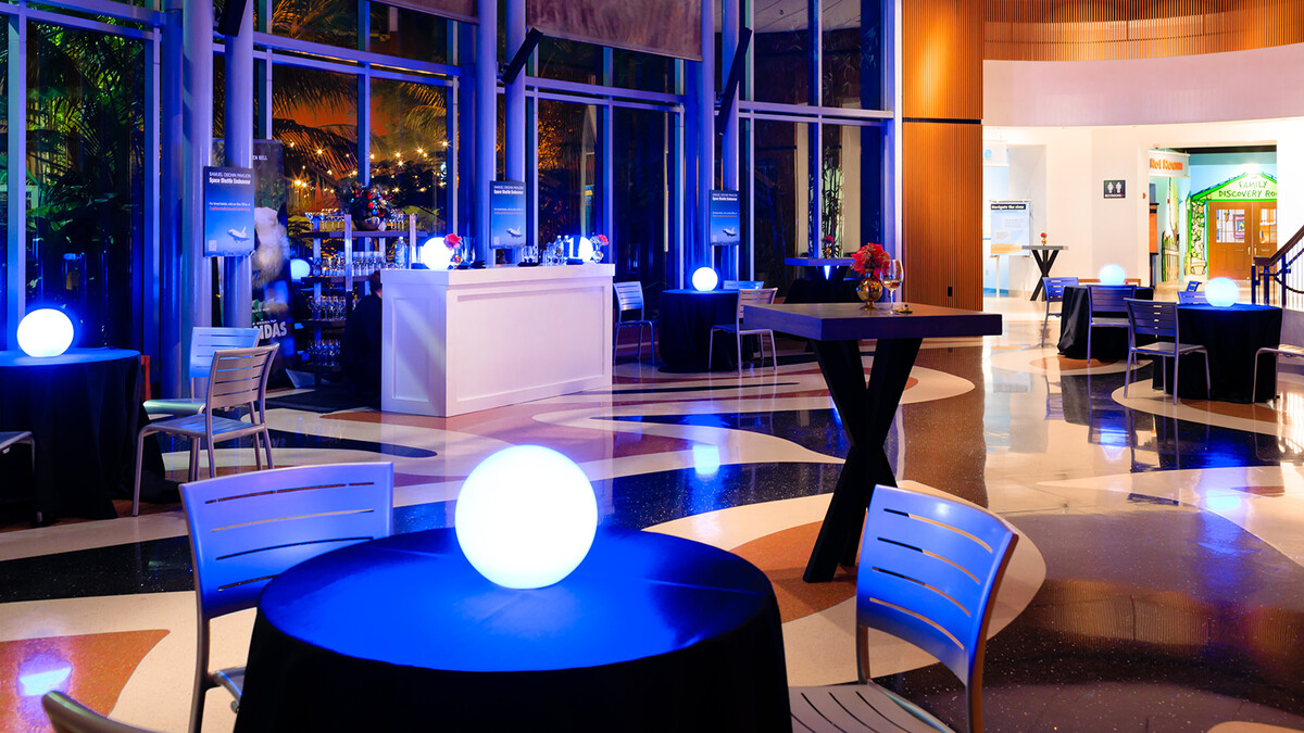 Night cocktail reception in Ecosystems atrium with intimate table groupings and glowing orb centerpieces