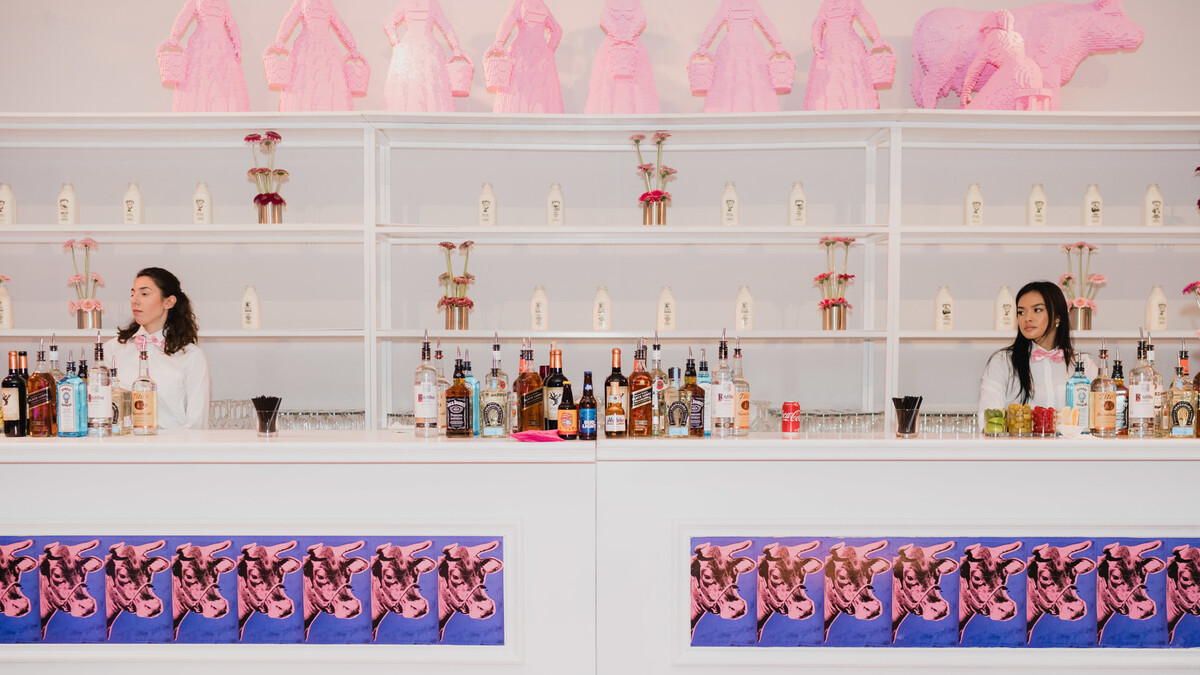 White bar decorated with purple and pink Andy Warhol cows and backbar decorated with Nathan Sawaya's pink eight maids a milking