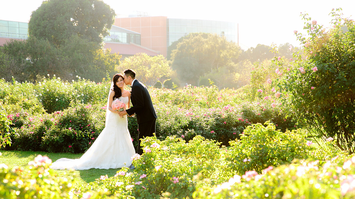 Bride and groom pose for a portrait in the Exposition Park Rose Garden