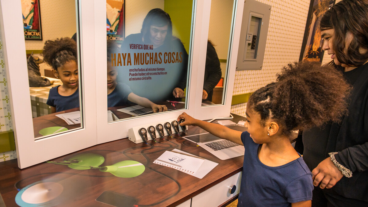 An adult and child explore an interactive exhibit about electrical safety.