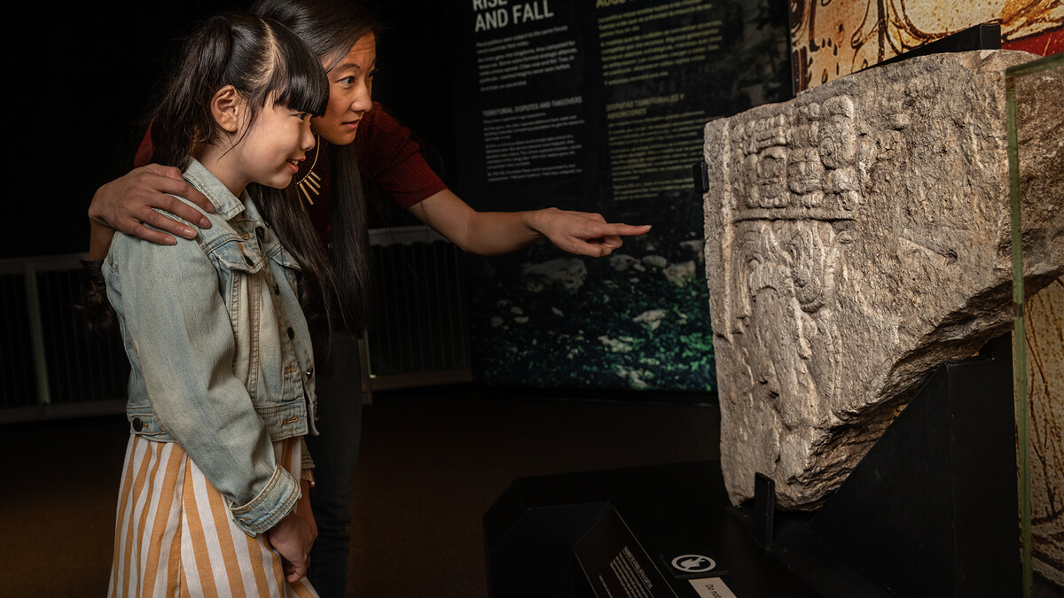 Mother and daughter admire a Maya stone carving.