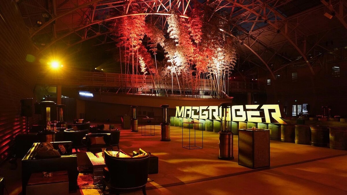 Big Lab event space is lit in red and orange event lighting and features lounge furniture and large letters spelling our MACGRUBER.