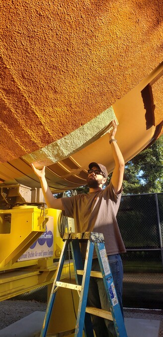 Assistant aerospace curator Perry holds up a piece of new foam to the external tank to check its fit.