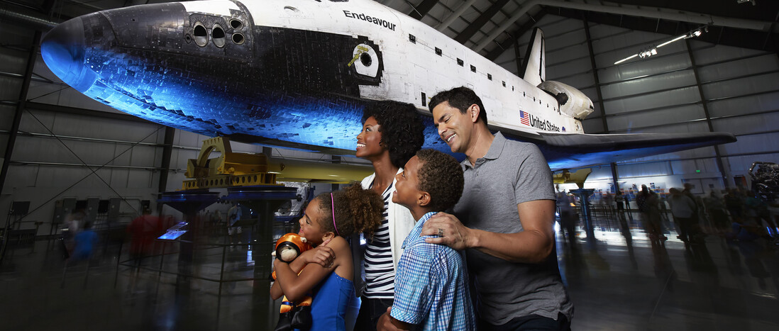 A diverse family group enjoys the space shuttle Endeavour display in the Samuel Oschin Pavilion.