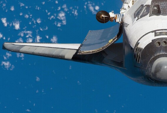 Endeavour in orbit with its payload bay doors open and Earth in the background